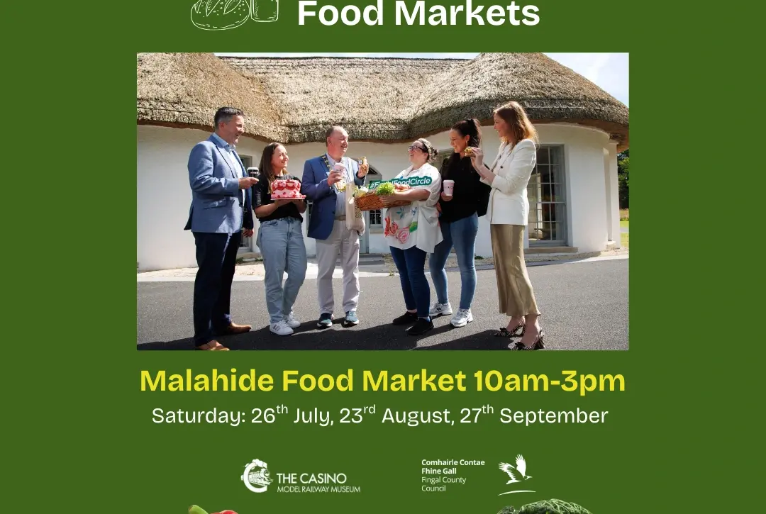 A group of people stand outside a thatched building, holding baskets of fresh produce, beneath the text "Fingal Food Markets." The Malahide Model Railway Museum welcome is featured alongside market dates. Fresh vegetables are displayed at the bottom.