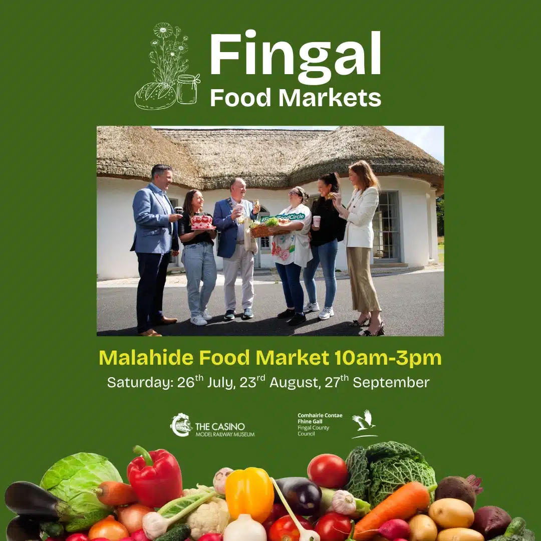 A group of people stand outside a thatched building, holding baskets of fresh produce, beneath the text "Fingal Food Markets." The Malahide Model Railway Museum welcome is featured alongside market dates. Fresh vegetables are displayed at the bottom.